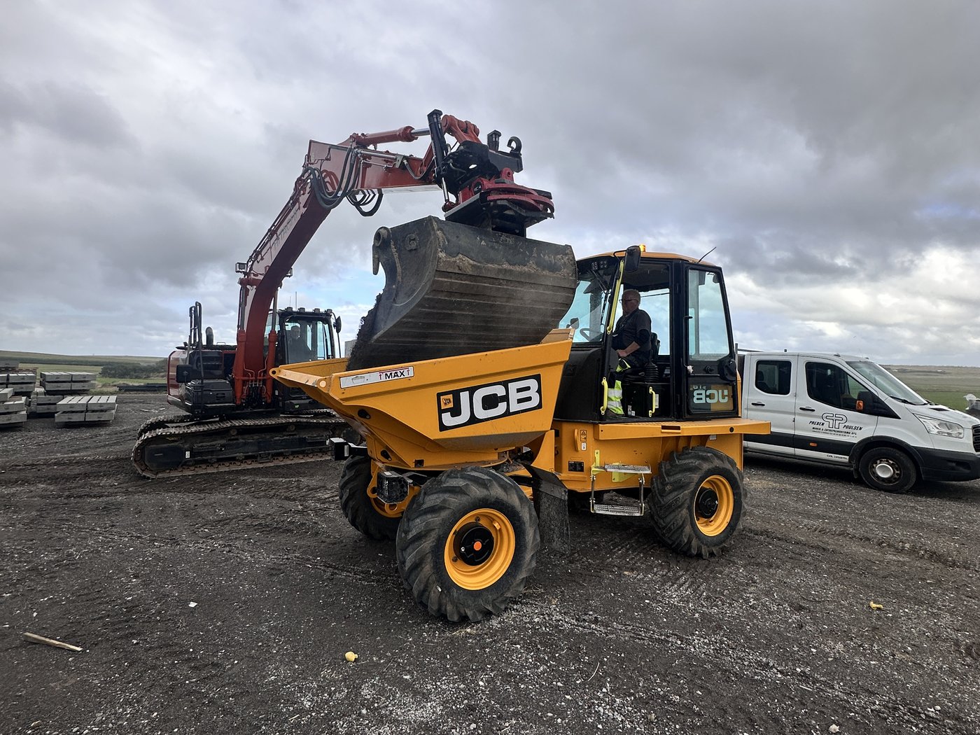 Gravemaskine læsser jord på JCB 6T-2 dumper